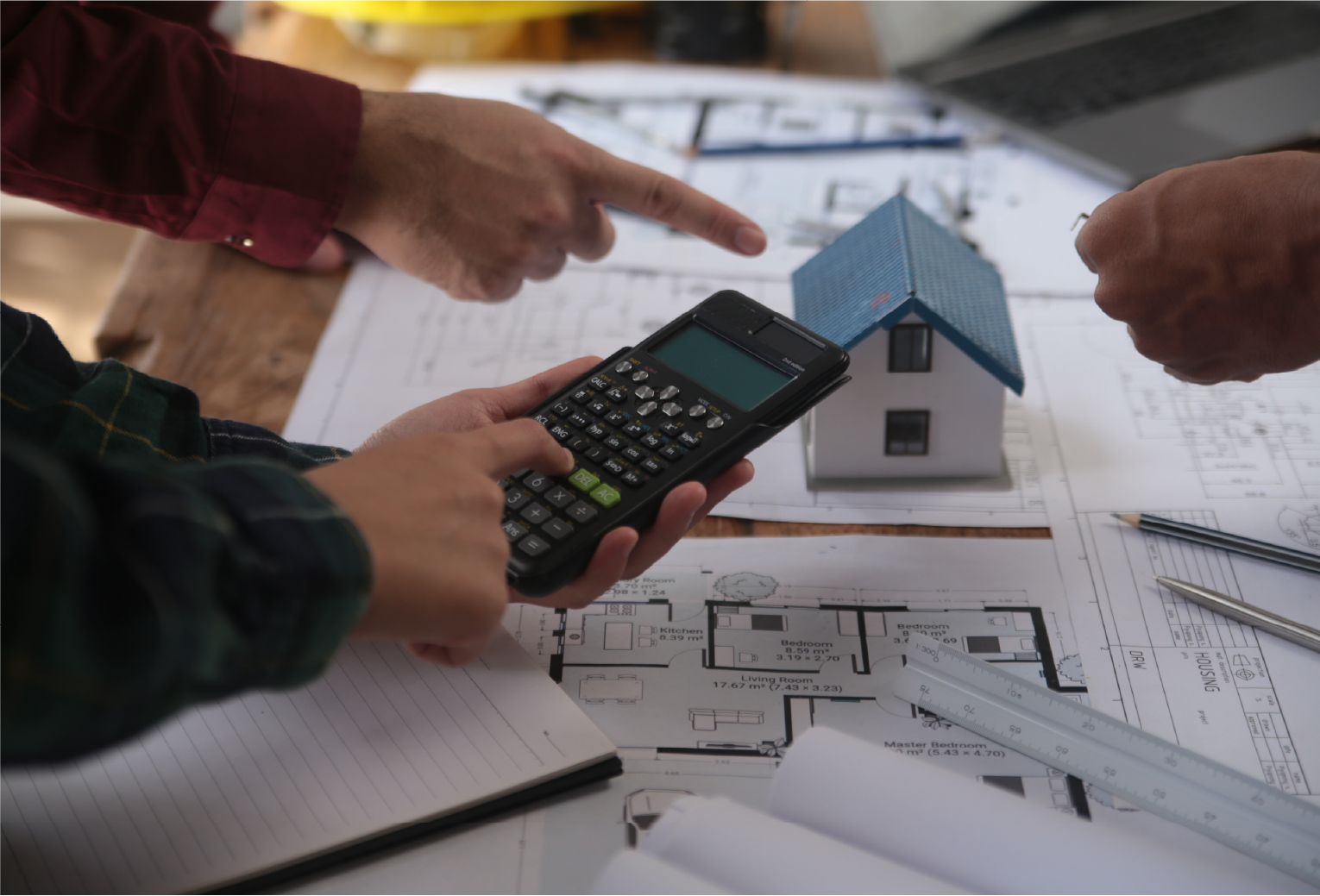 people gathered around house plans and calculator