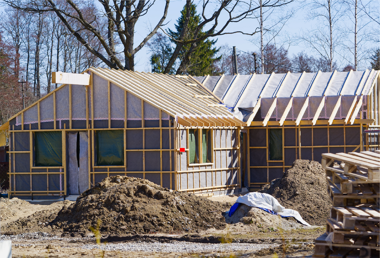home in mid construction with wooden structure and windows installed.